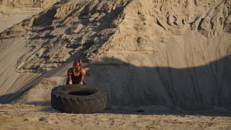 girl on sand quarry pushing wheel in training crossfit workout