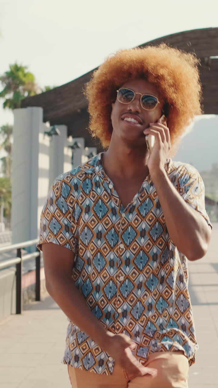 Young Man with Afro Hair Talking on Smartphone and Gesturing Outdoors