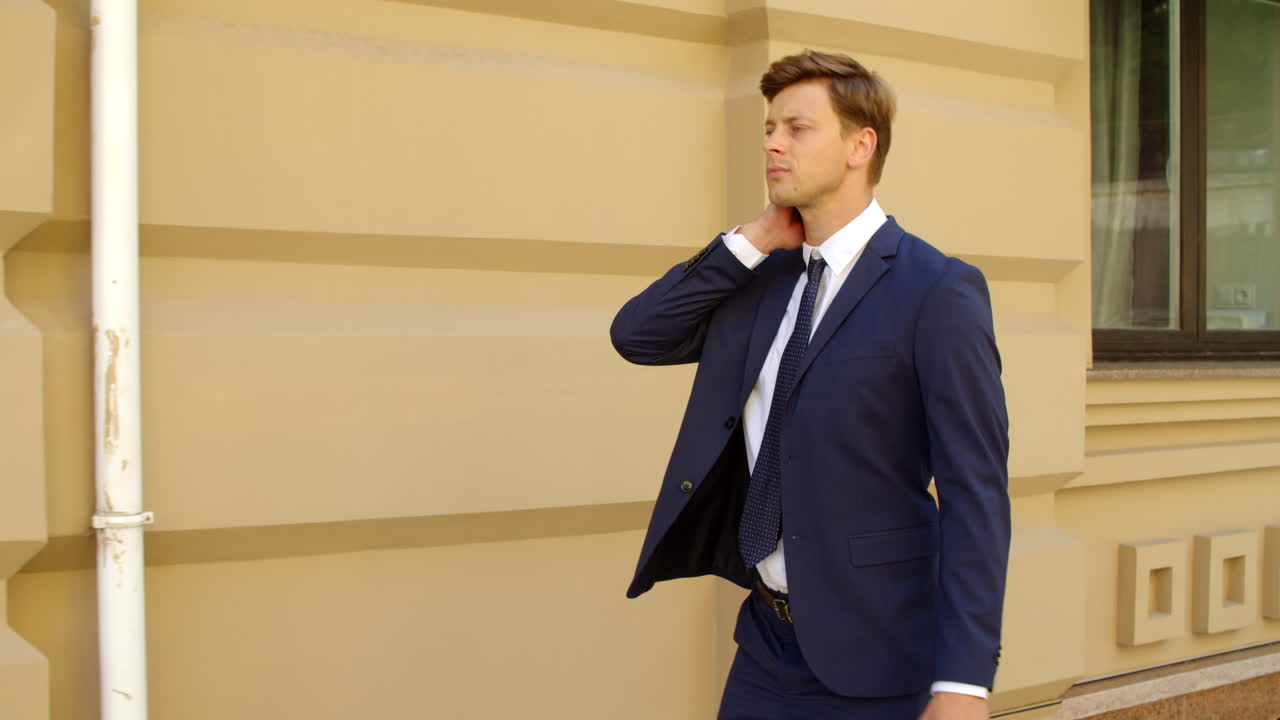 hombre ejecutivo de primer plano caminando solo por la calle. hombre flexionando el cuello en la acera