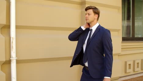 Closeup-executive-man-walking-alone-at-street.-Guy-flexing-neck-at-sidewalk