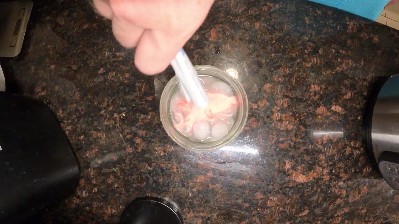 Top down close up of a man pouring lemonade powder into ice-chilled water and stirring vigorously for preparing refreshing summer drink