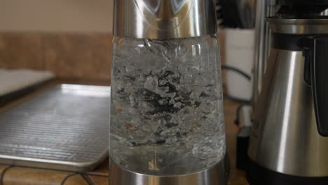 water boiling and bubbling in clear glass kettle by coffeemaker