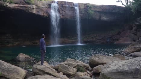 Junger-Mann,-Der-Den-Natürlichen-Wasserfall-Genießt,-Der-Morgens-Vom-Berggipfel-Fällt