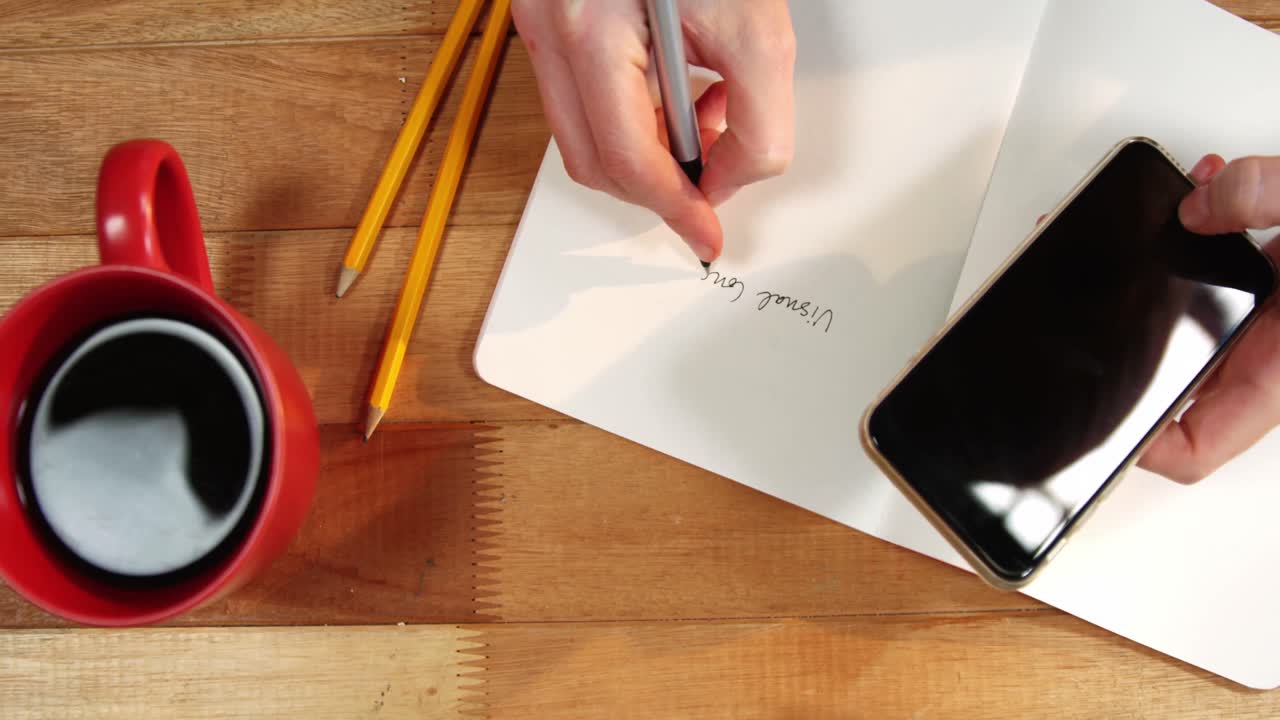 Hand of businesswoman writing on book at desk