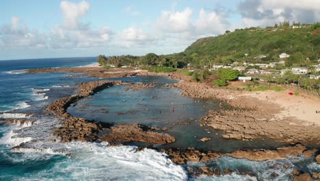 low panning aerial shot of snorkelers and swimmers in shark cove on the north shore of o'ahu, hawaii