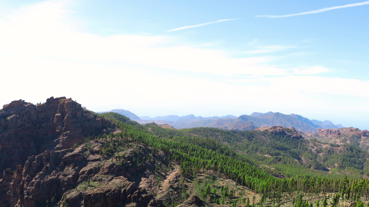 Paesaggio con vista panoramica su cime di colline e area circostante ricca di alberi e montagne, paesaggio vulcanico durante giornate di sole sull'isola di Gran Canaria, ripresa in slow motion 4K a 60fps