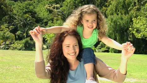 Girl-on-the-shoulders-of-mom-smiling-at-the-camera