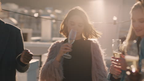 group of diverse friends hanging out dancing together enjoying rooftop party at sunset drinking alcohol having fun on weekend celebration