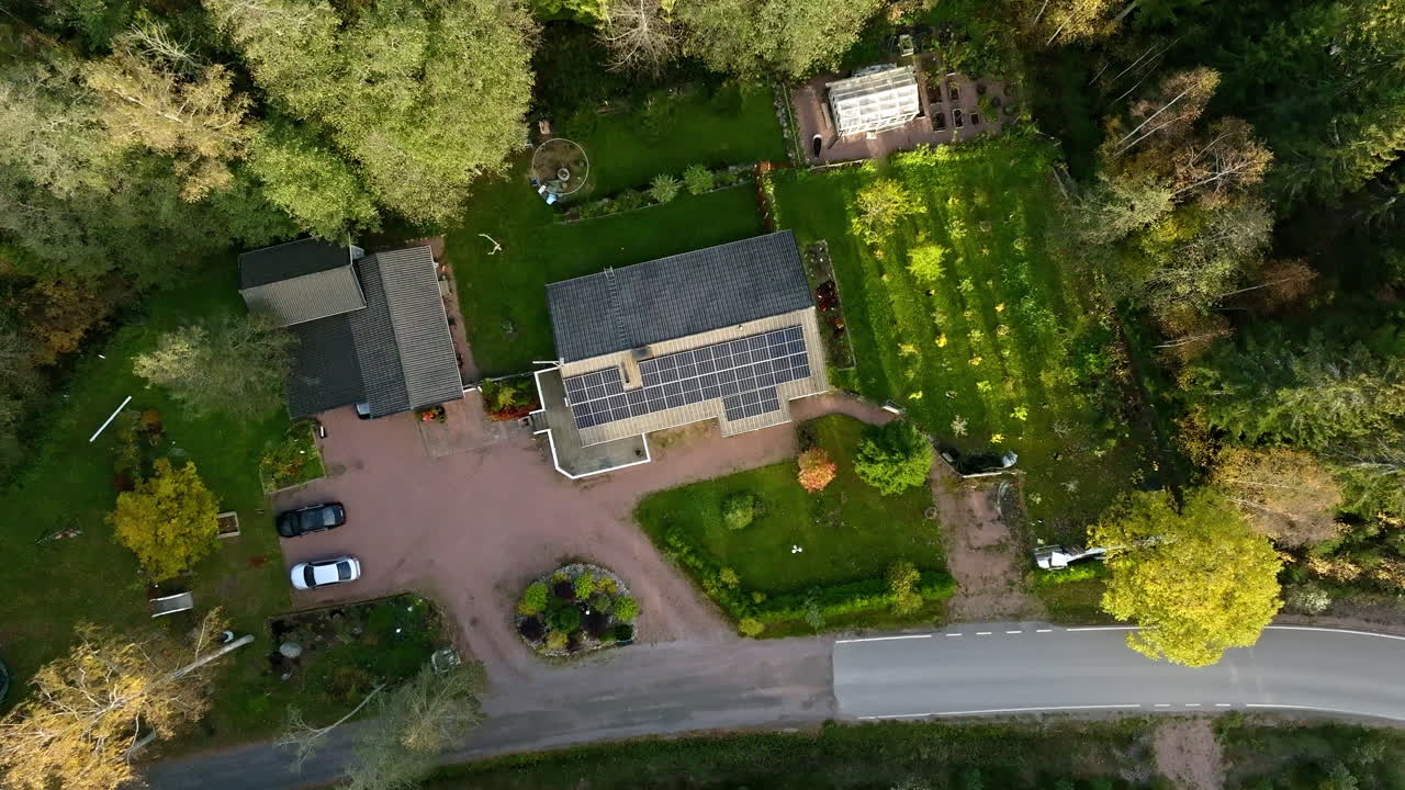 Aerial view rotating above a sustainable house in middle of sunlit autumn forest
