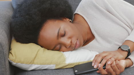 tired black woman texting on a phone while resting