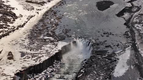 aerial of selfoss waterfall in snowy landscape with frozen river and basalt cliffs in iceland