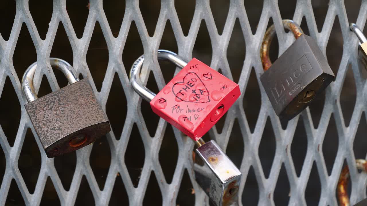 cerca o disparo de detalle de tres cerraduras colgando de una valla