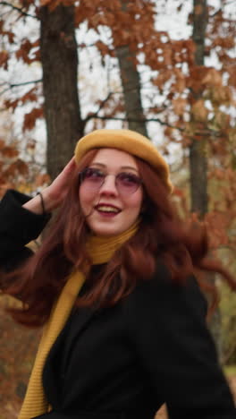 mujer alegre con abrigo negro y boina amarilla juega en las hojas de otoño, girándose con una sonrisa, capturando la esencia del espíritu lúdico del otoño