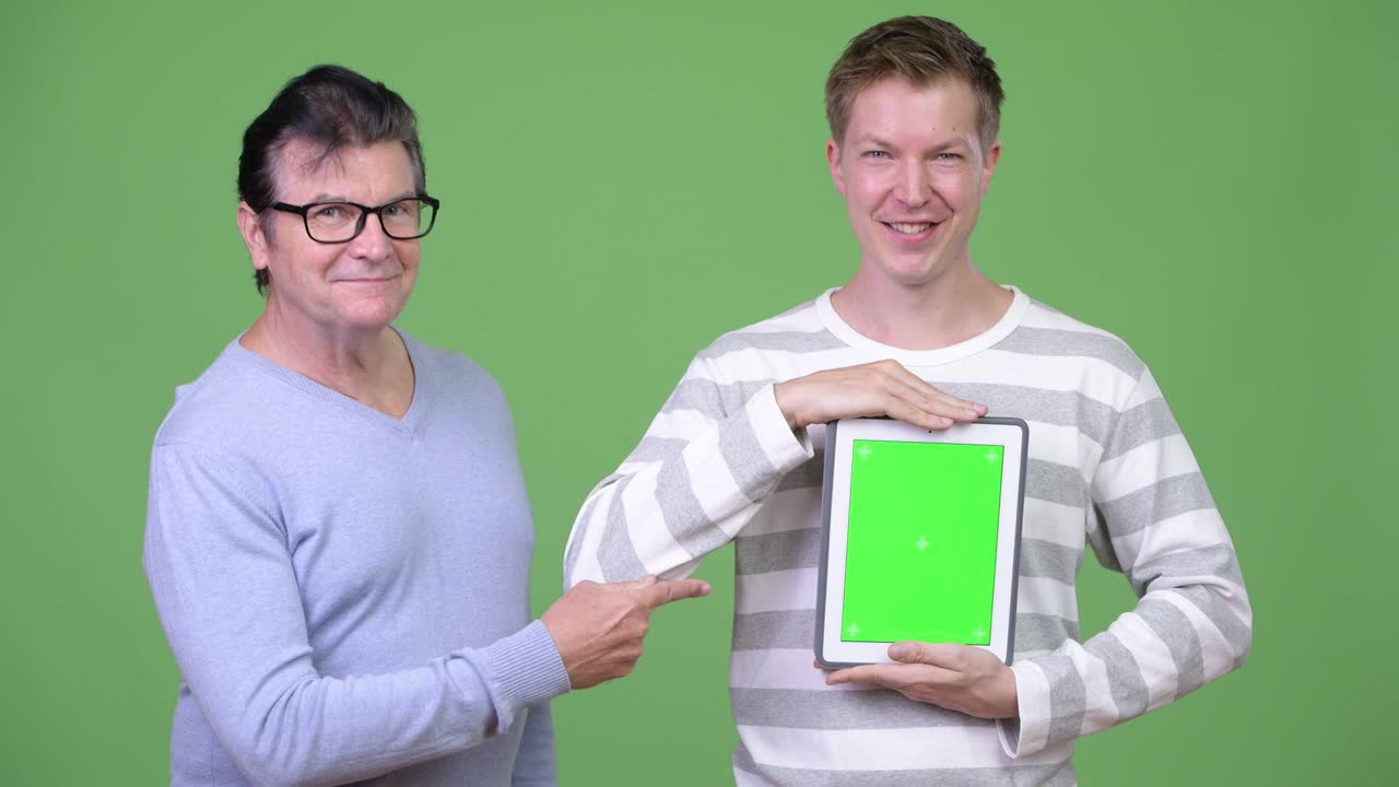 Senior handsome man and young handsome man showing digital tablet together