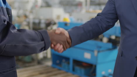 unrecognizable factory worker and businessman shaking hands