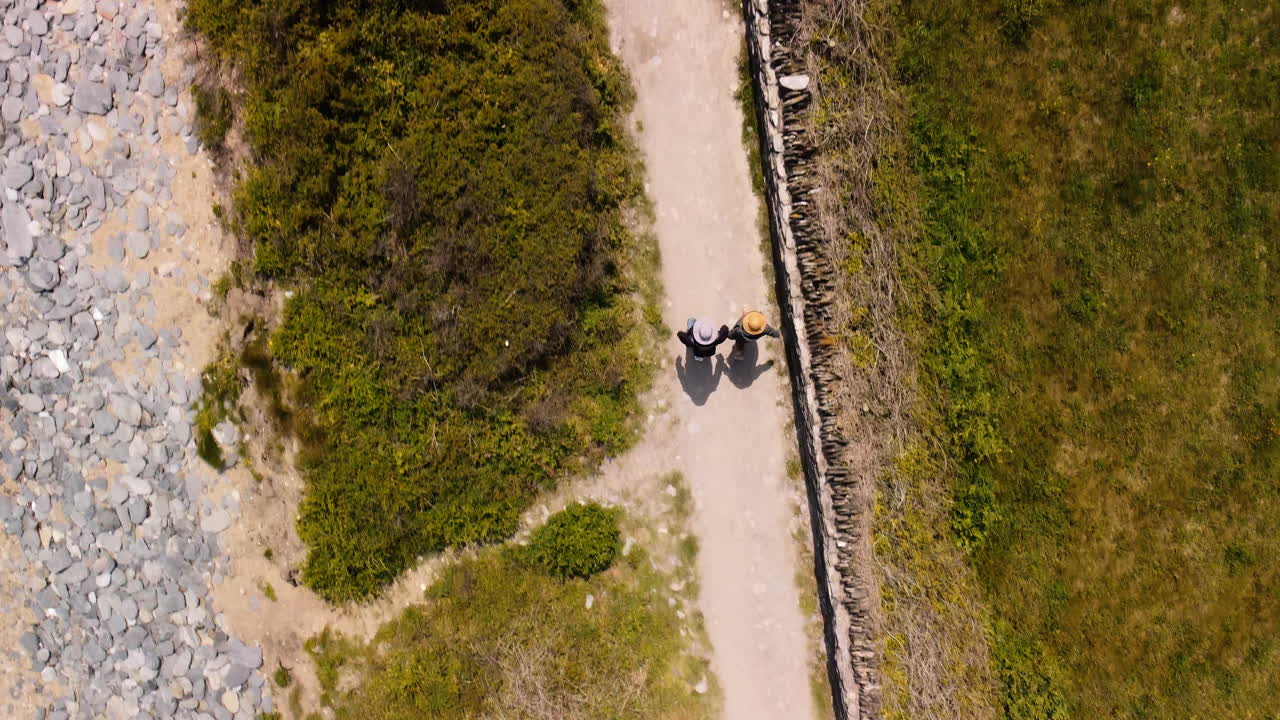 una pareja caminando por un sendero junto a la playa