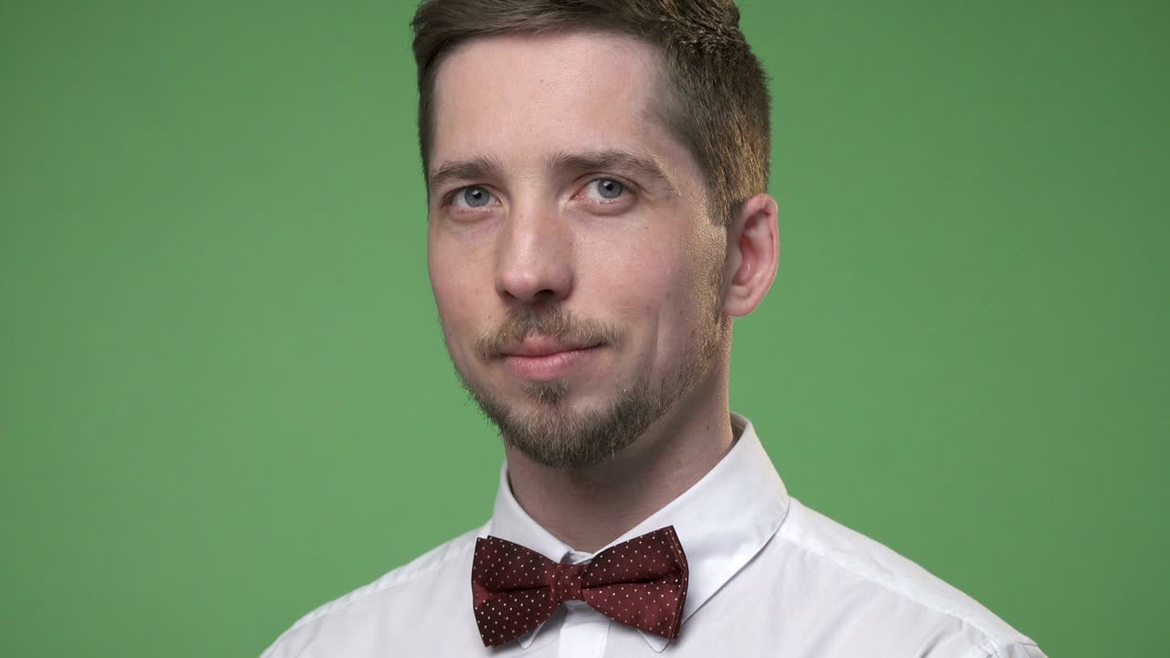 Primo piano di un giovane studente in camicia bianca con papillon, sfondo green screen chroma key