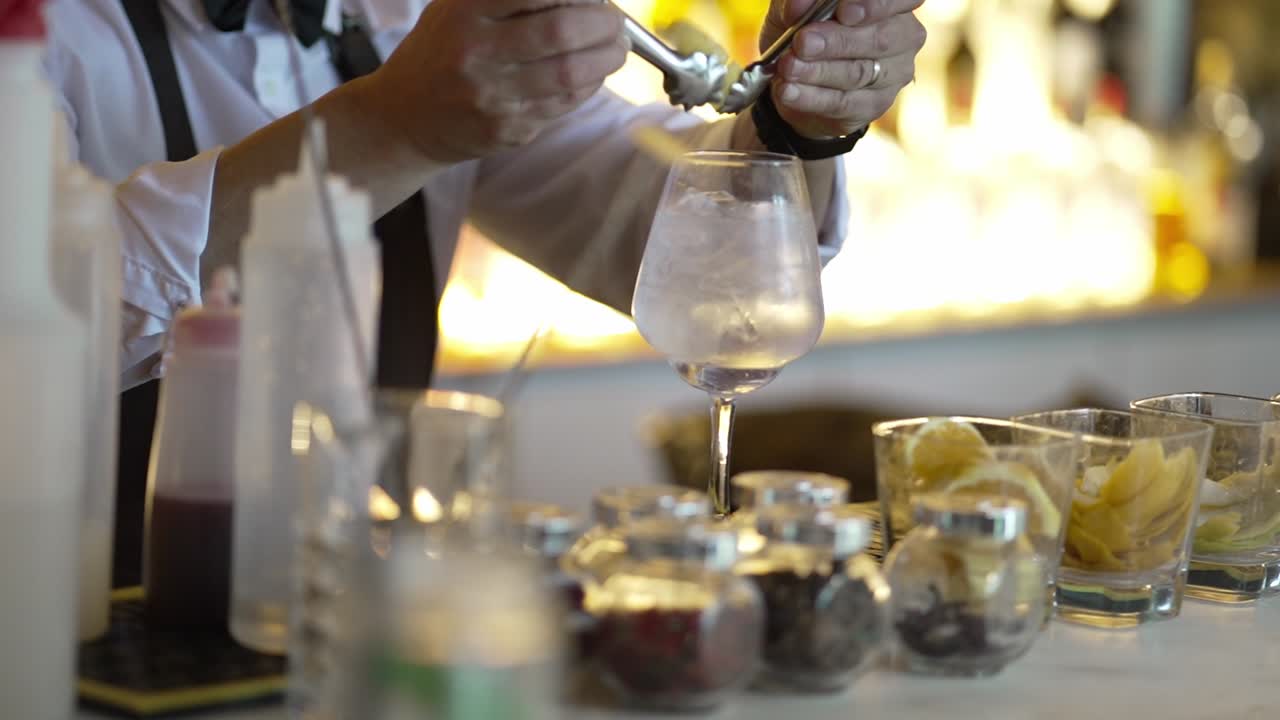 Bartender garnishing cocktail at bar with various fresh ingredients and jars