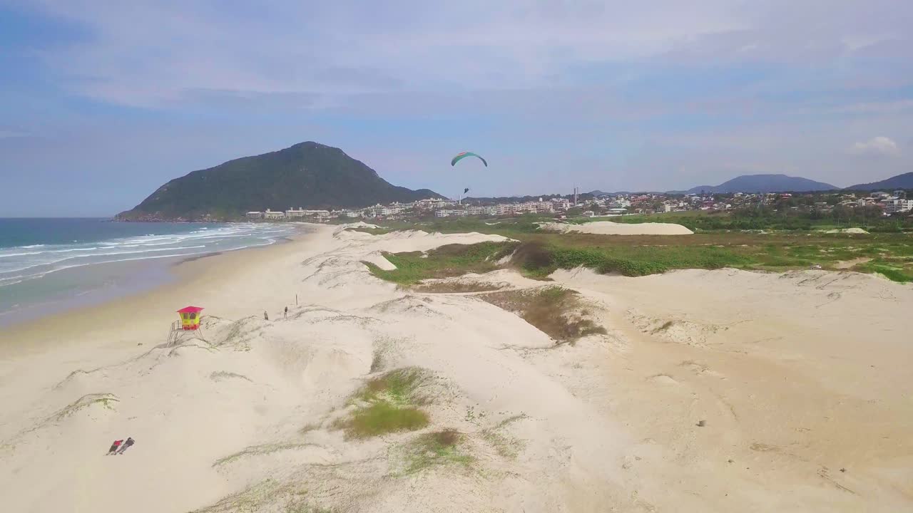 tomada aérea de un avión no tripulado de paramotor volando sobre una playa en brasil, florianópolis