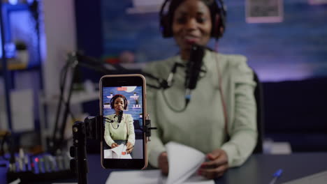 Focused-shot-on-smartphone-recording-african-blogger-woman-talking