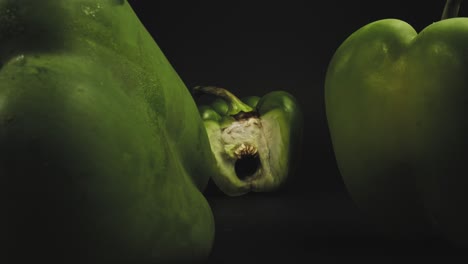 three fresh green bell peppers, one sliced open