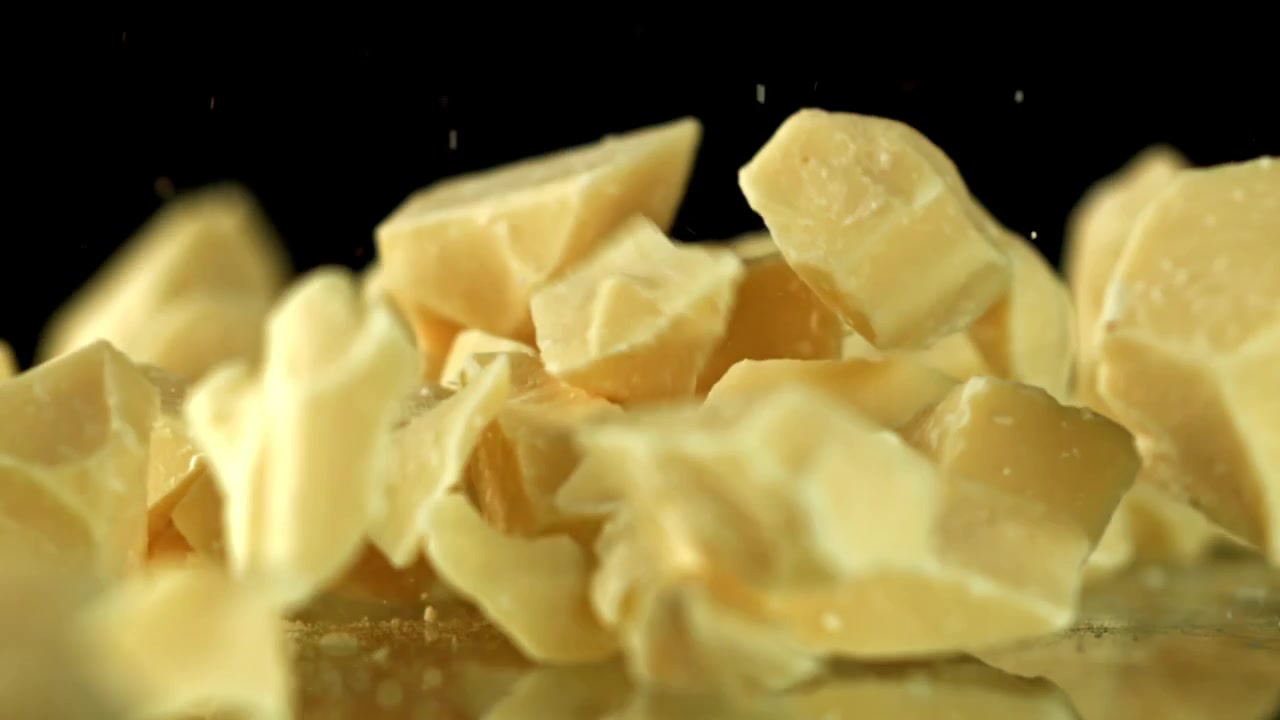 White Chocolate Pieces Falling in Slow Motion on Black Background