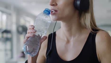 Handheld view of female athlete drinking water after hard workout