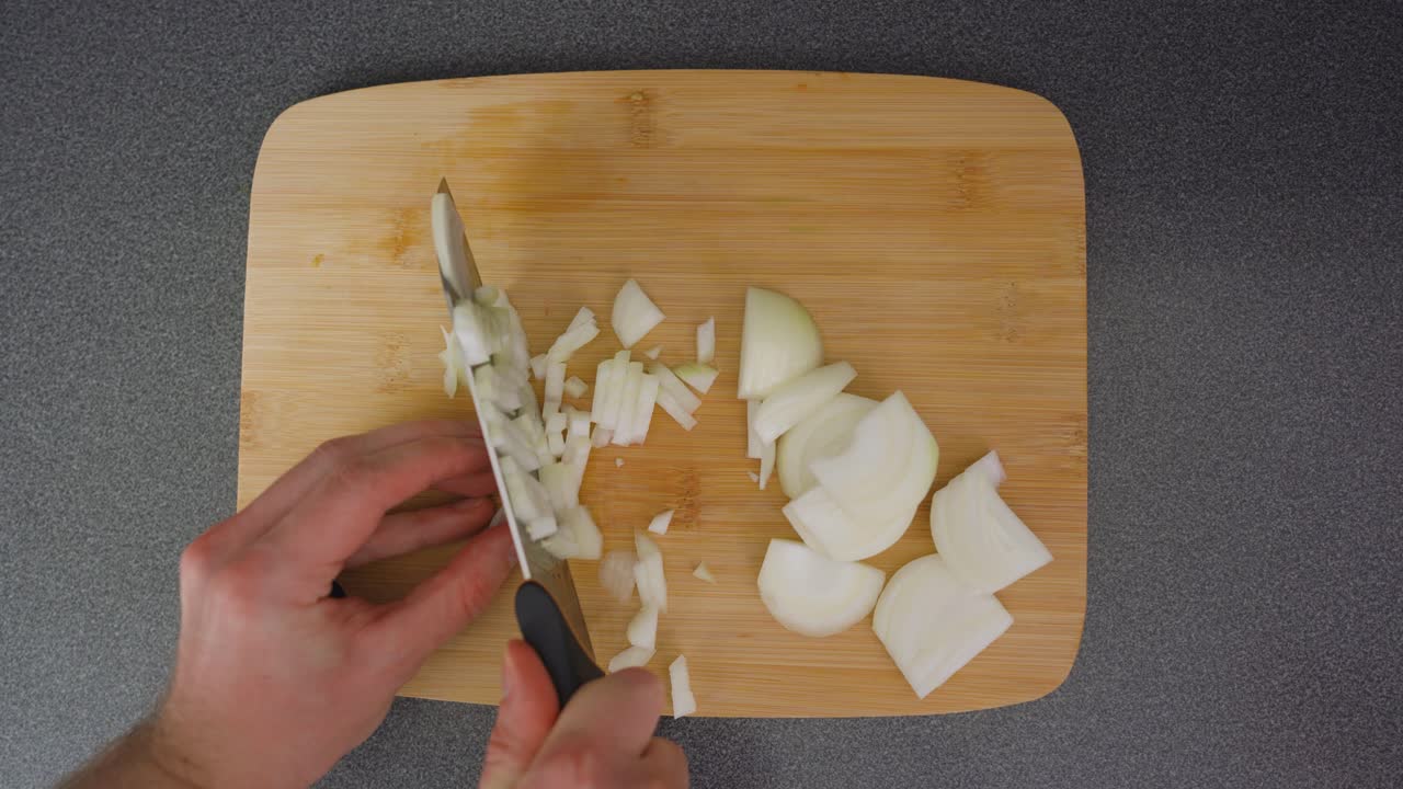 Man chopping a brown onion into small pieces