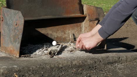 Man-twirls-a-marshmallow-over-hot-ash-on-a-stick