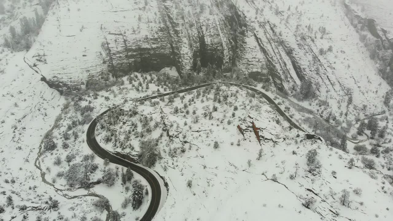 Aerial push in shot of a country road during a fresh snowfall in the mountains of California.