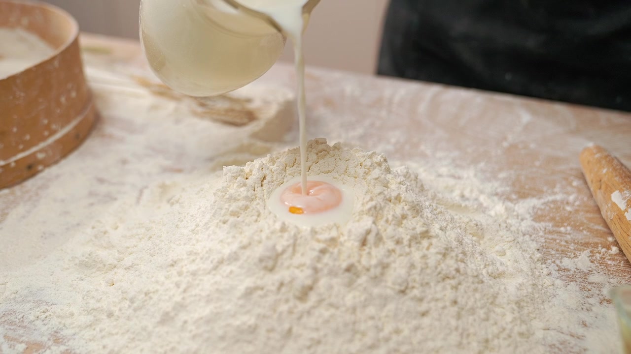 Pouring Milk onto Egg Yolk and Flour for Baking Dough