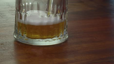 golden amber beer is poured into glass on counter, close up view