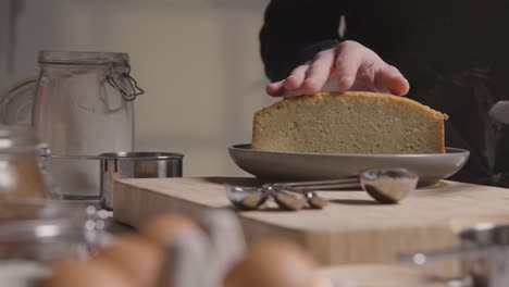 primer plano del hombre en la cocina de casa cortando pastel recién horneado en la superficie de trabajo