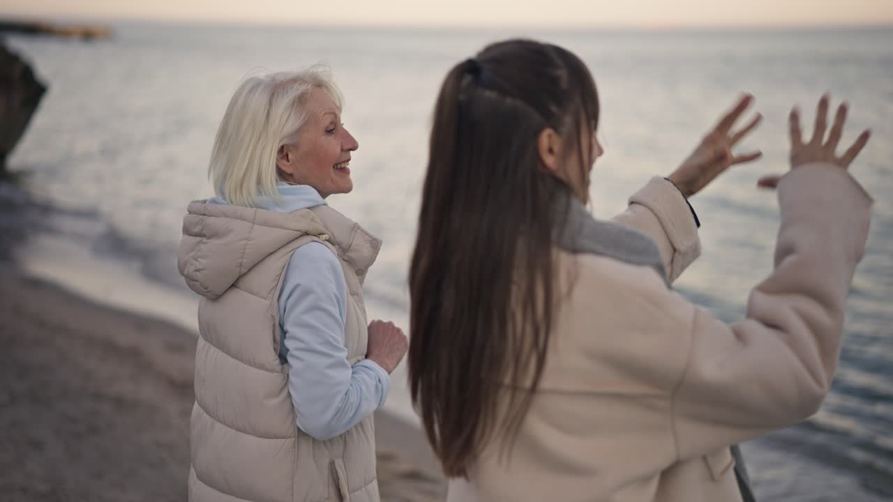Grandmother and granddaughter walking on the beach