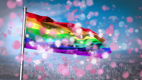 animation of rainbow flag with white and pink flickering spots over blue sky and cityscape