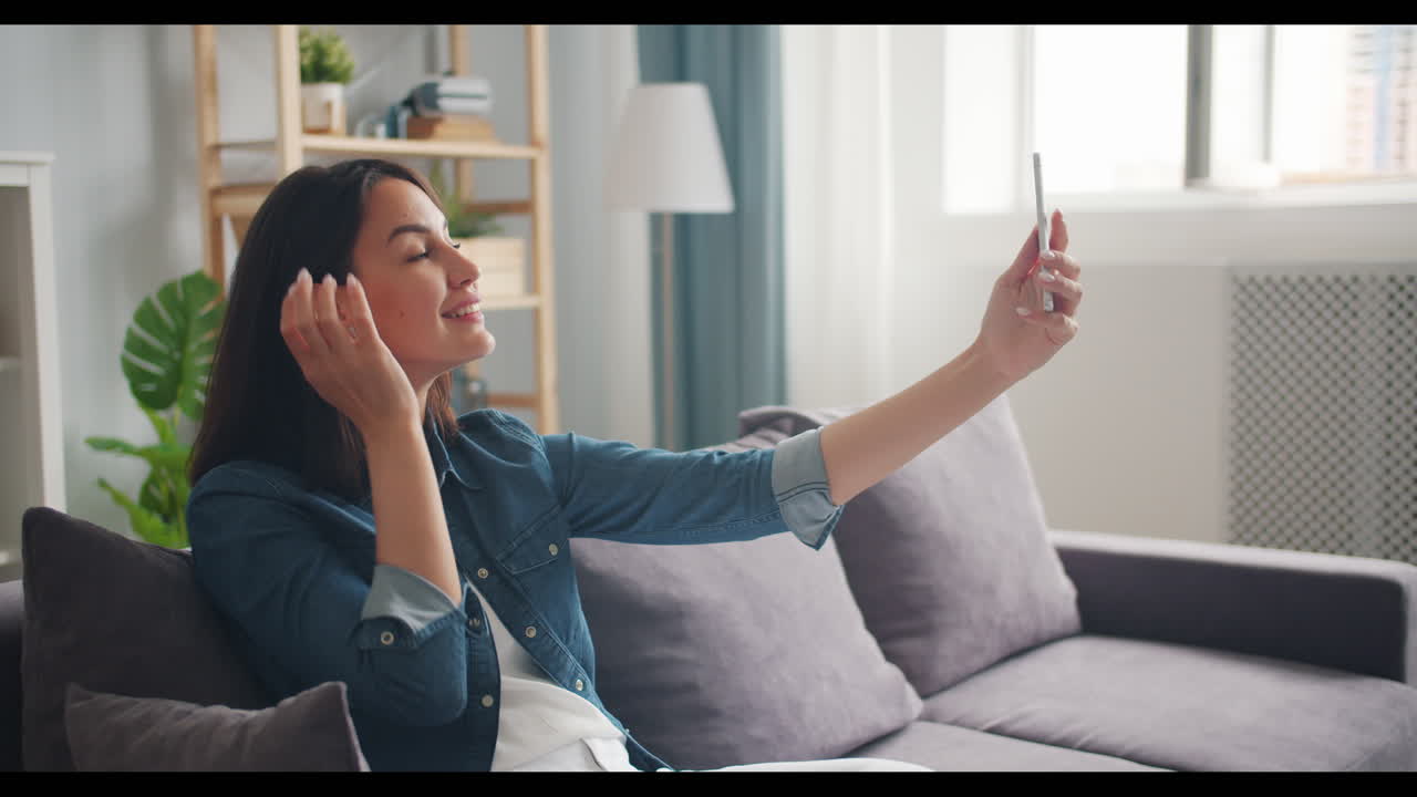 una mujer tomando una selfie en el sofá.