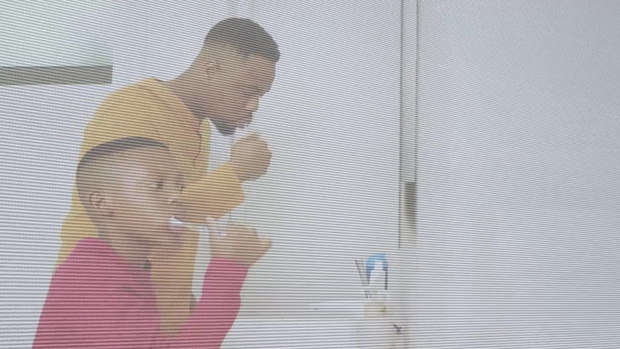 Father reaching for faucet, guiding son brushing with toothbrush at mirror, teaching oral health