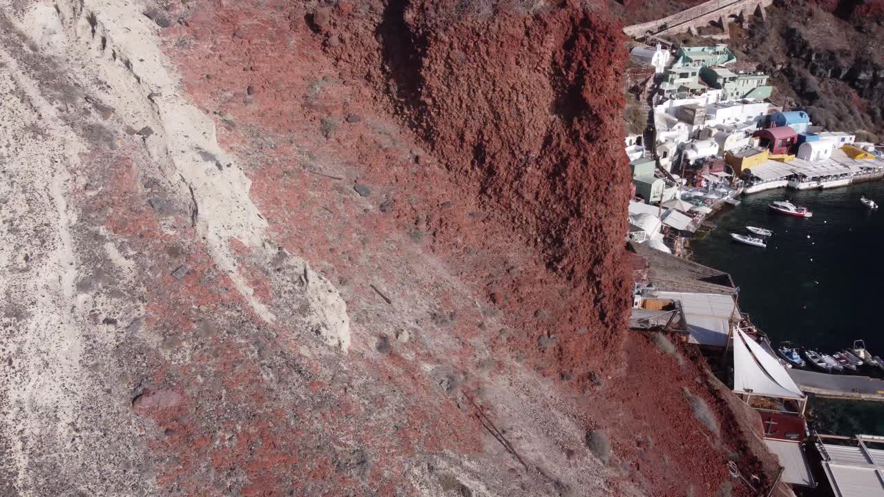 이아 산토리니(oia santorini) 근처 바위 뒤에 있는 아름다운 아무디 항구를 드러내는 드론 샷