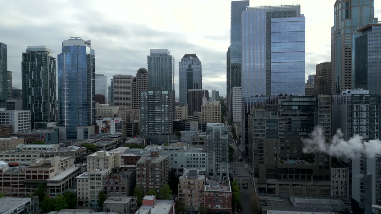 Aerial drone shot of dense, polluted cityscape and buildings along downtown Seattle during overcast day - Washington, USA