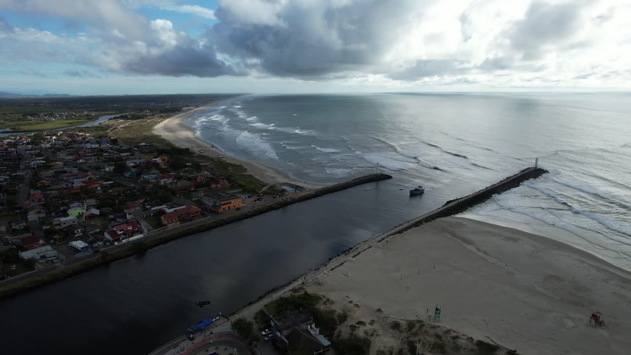 drone shot showing a canal with boat leading to the sea, soft dawn light with clouds