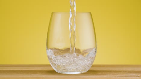 total view pouring fresh clear sparkling water in a drinking glass on isolated