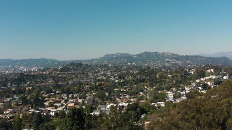 flying over an la neighbor with the hollywood sign on the distant hills near beverly hills in los angeles