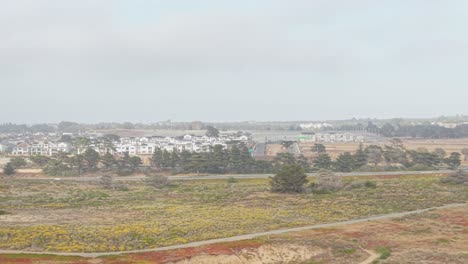 a wide aerial reveals fort ord’s layered landscape, textured by brush and dunes, and edged by distant highway lanes.