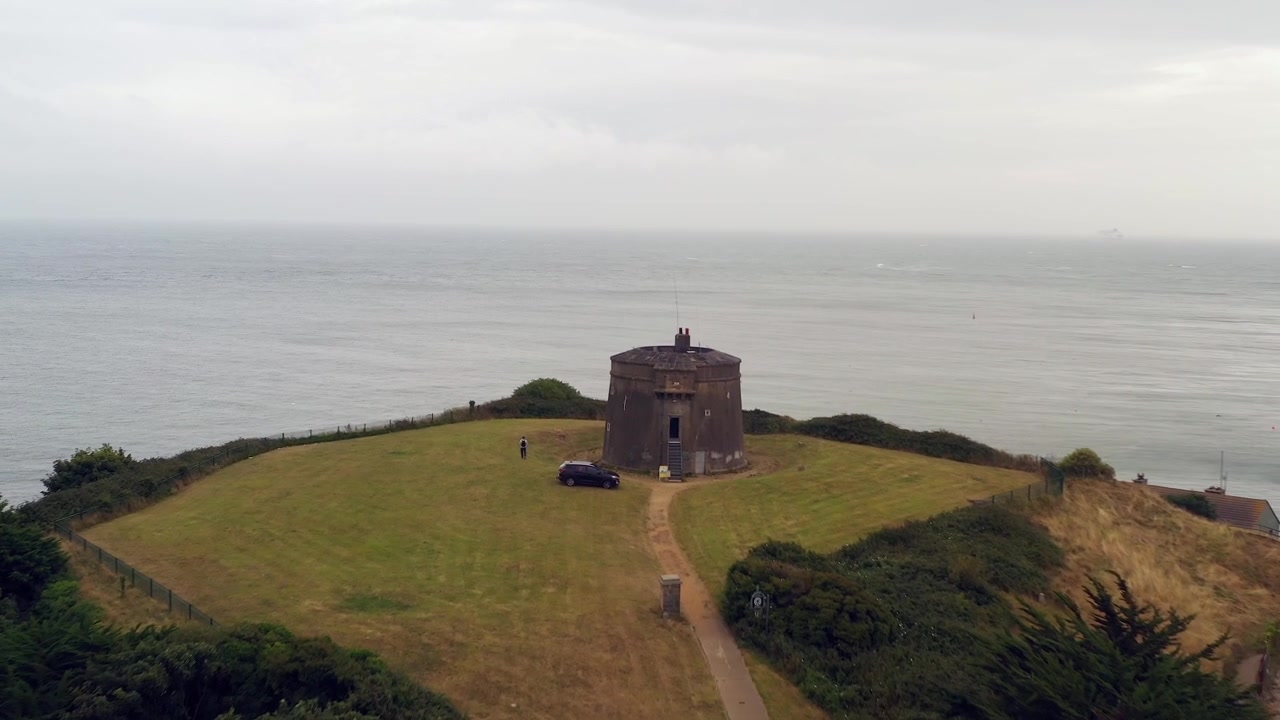 Ripresa aerea in allontanamento su acque aperte e nebbiose verso la Torre Martello che si affaccia sull'oceano a Howth, Dublino Nord, Irlanda