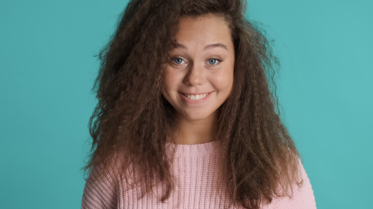 Caucasian curly haired woman nodding in front of the camera.