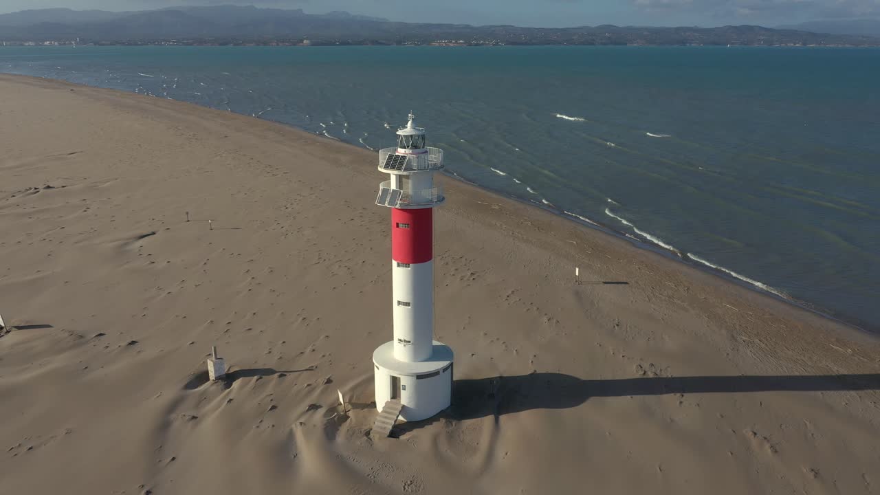 fangar faro, o delta del ebro, de pie solo en una amplia playa de arena advirtiendo barcos de peligro de navegación donde el río se encuentra con el mar en españa