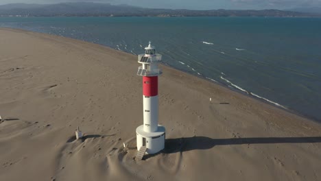 Fangar-lighthouse,-or-delta-del-ebro,-standing-alone-on-wide-sandy-beach-warning-ships-of-navigational-hazard-where-river-meets-sea-in-Spain