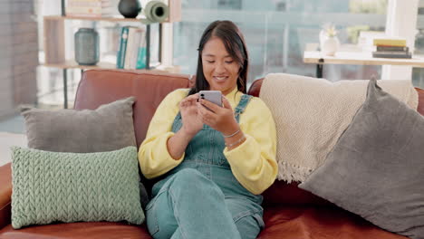 Smile,-happy-and-Asian-woman-with-phone-on-sofa-to