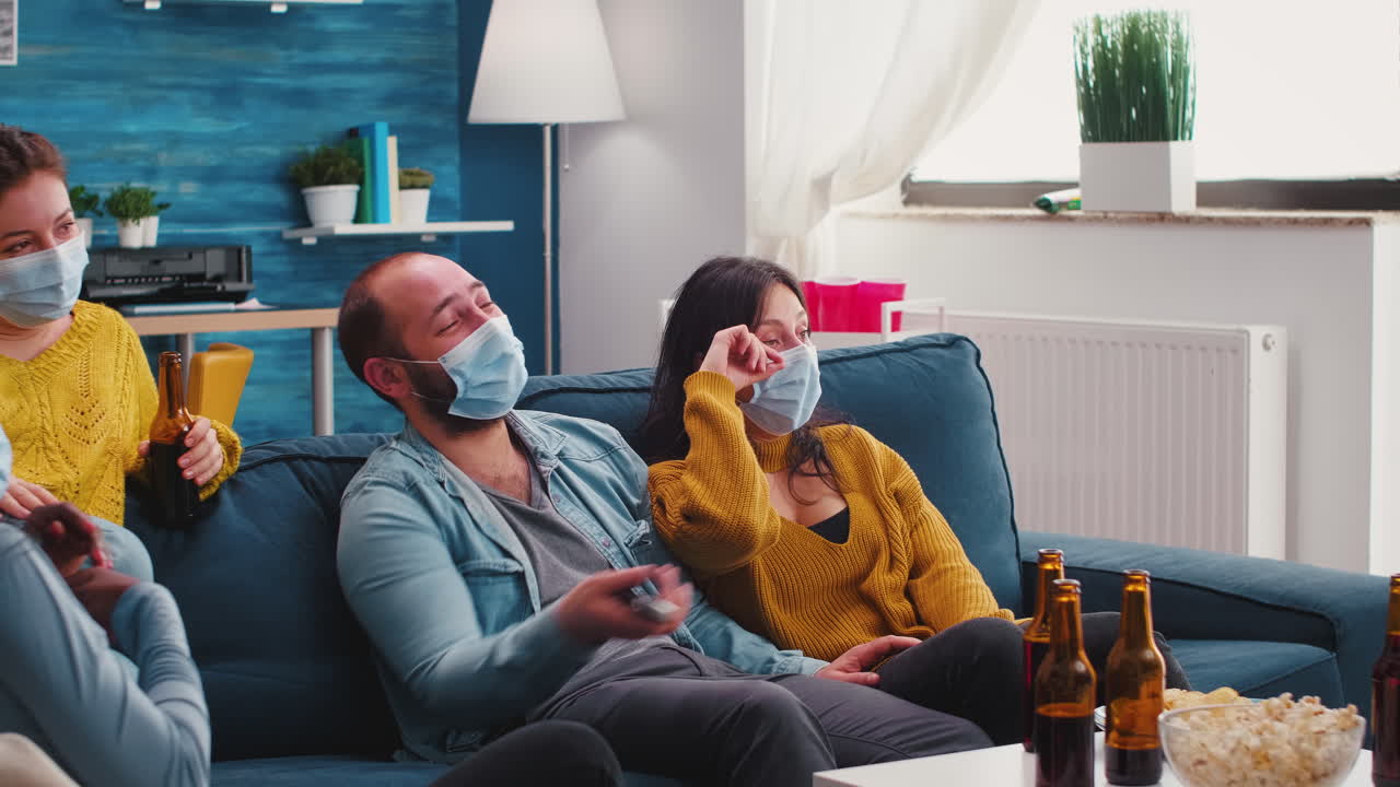 Multiethnic friends laughing looking at movie on tv