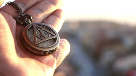 handheld pocket watch with deathly hallows symbol